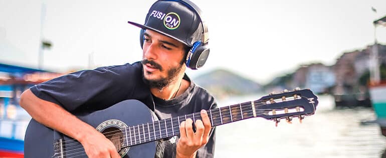 Artita Dry Som tocando violão e usando fones de ouvido