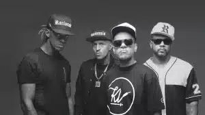 Foto preto e branco mostra os 4 membros do grupo Racionais Mcs, olhando para a camera.