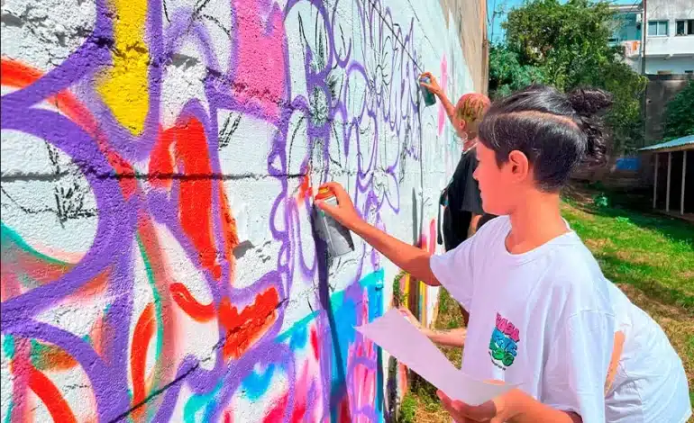 Foto mostra adolescente pintando parede com tinta spray em uma aula de Graffiti, comum na Cultura Hip Hop RS