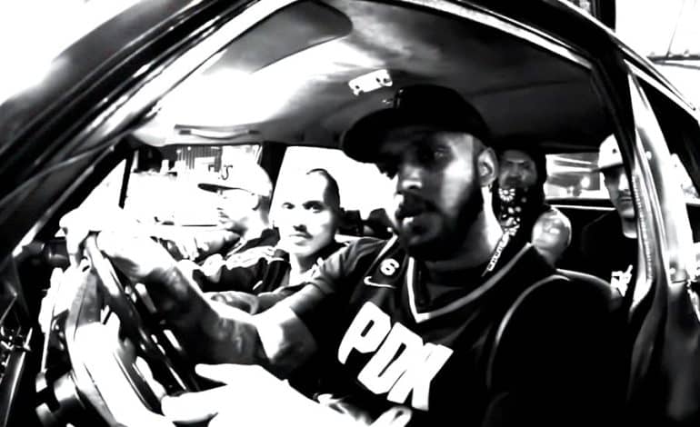 Foto mostra Emcee Canela e alguns amigos dentro de um carro, numa foto preto e branco